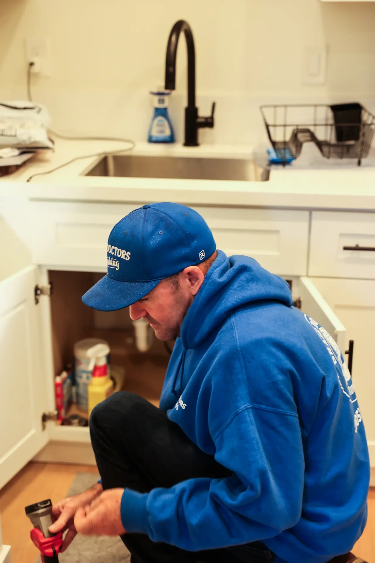 Drain Doctors Plumbing technician working on a clogged kitchen sink drain