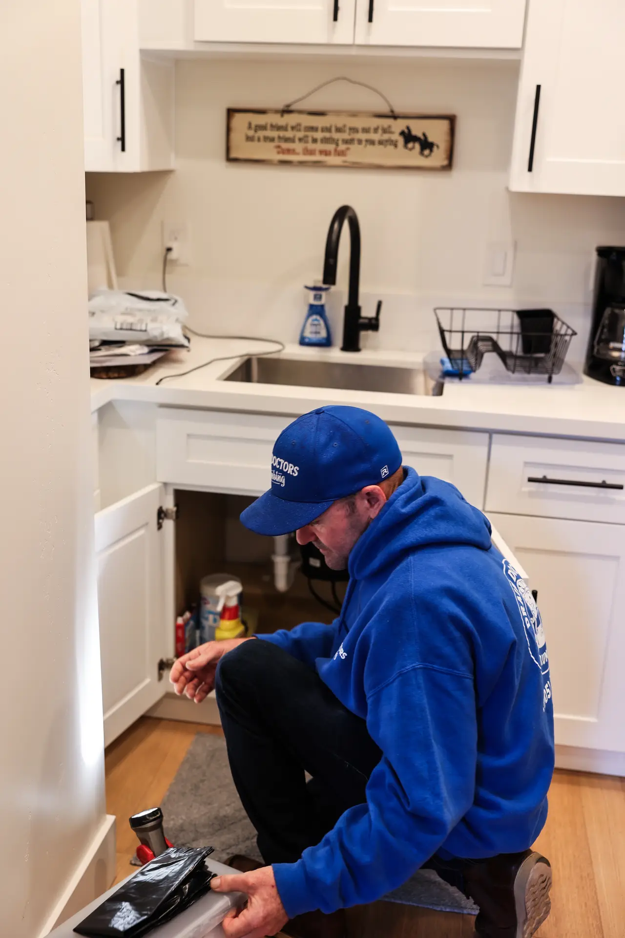 Drain Doctors Plumbing technician working on a kitchen sink drain in a home