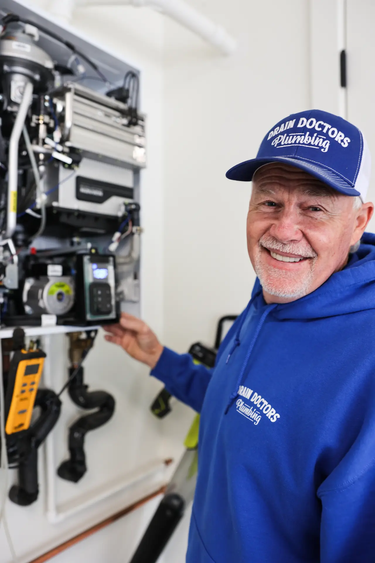 Drain Doctors Plumbing technician checking the inside of a wall-mounted water heater