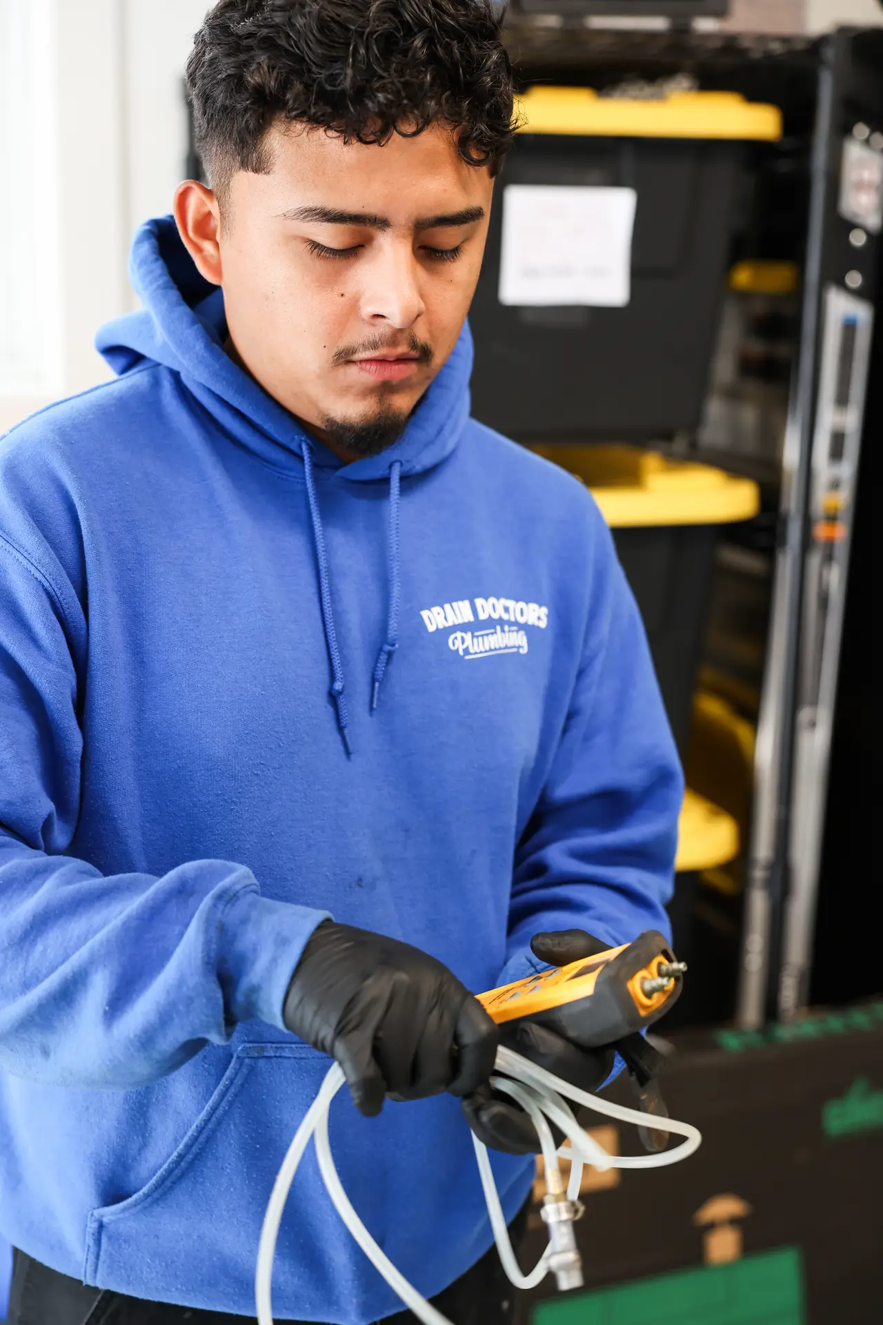 Drain Doctors Plumbing technician in gloves holding a digital gas pressure tester and its tubing