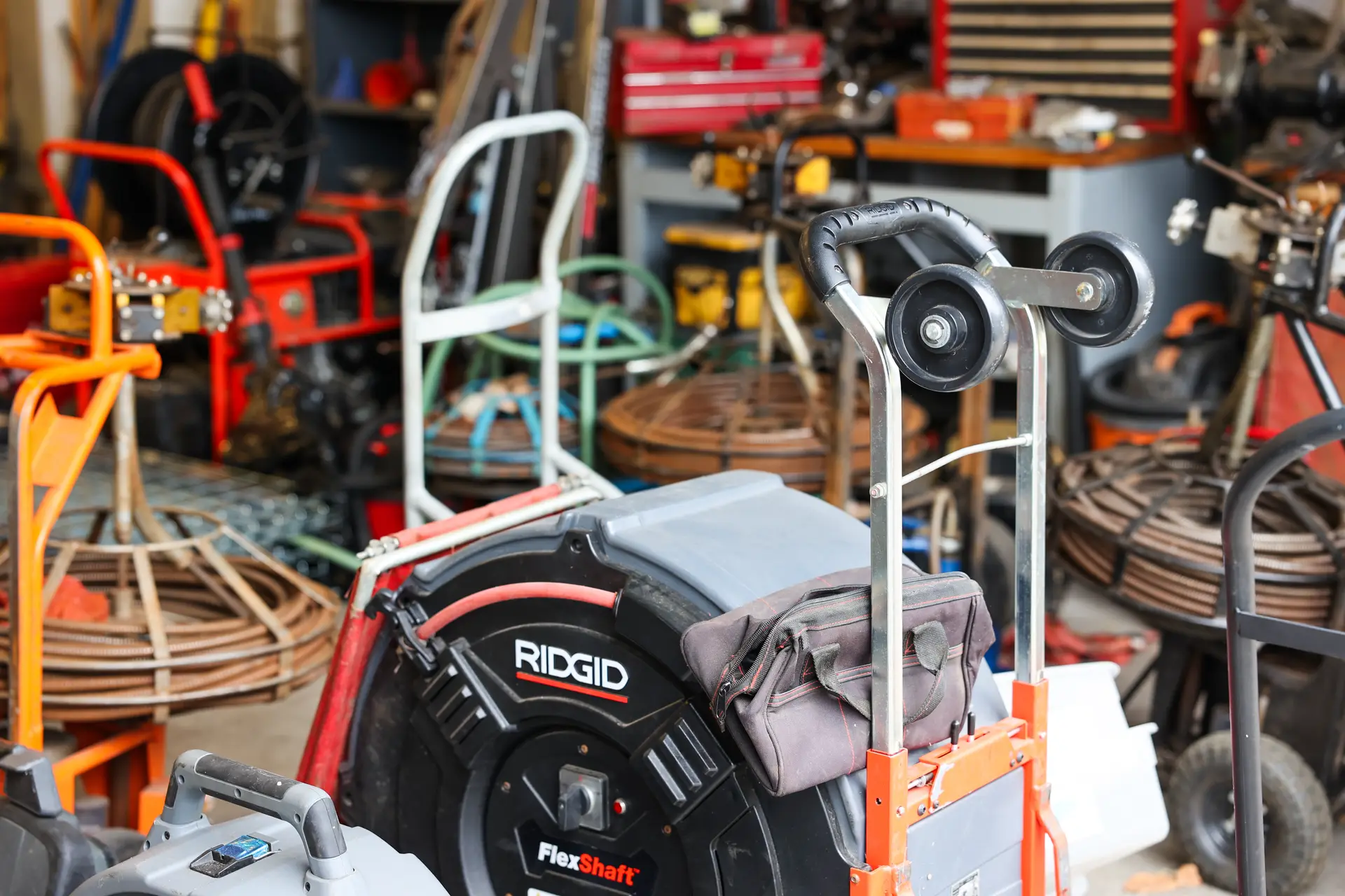 Drain cleaning machines and coiled drain cables lined up in the Drain Doctors Plumbing shop