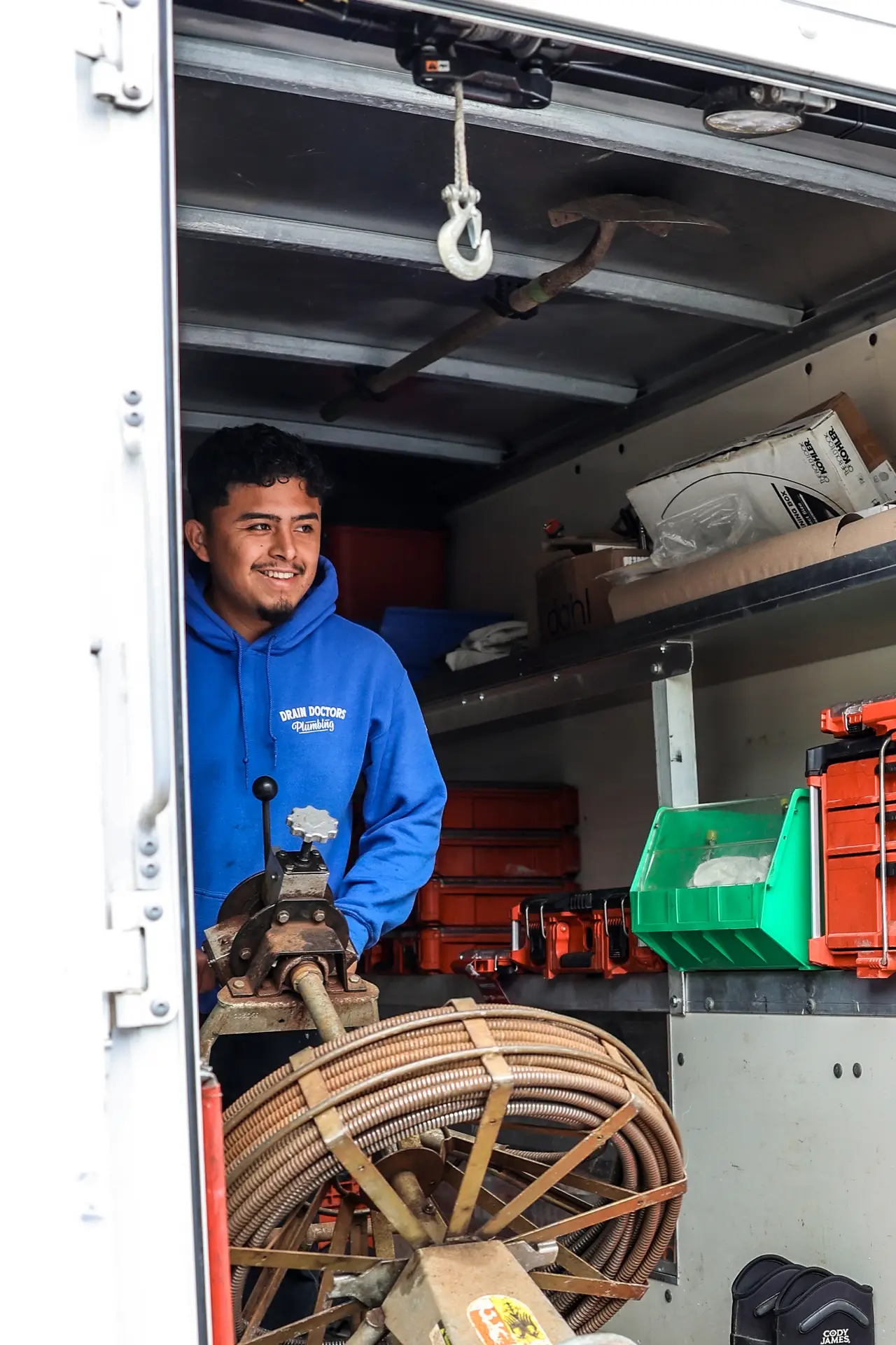 Drain Doctors Plumbing technician loading a drain cleaning machine into a service truck