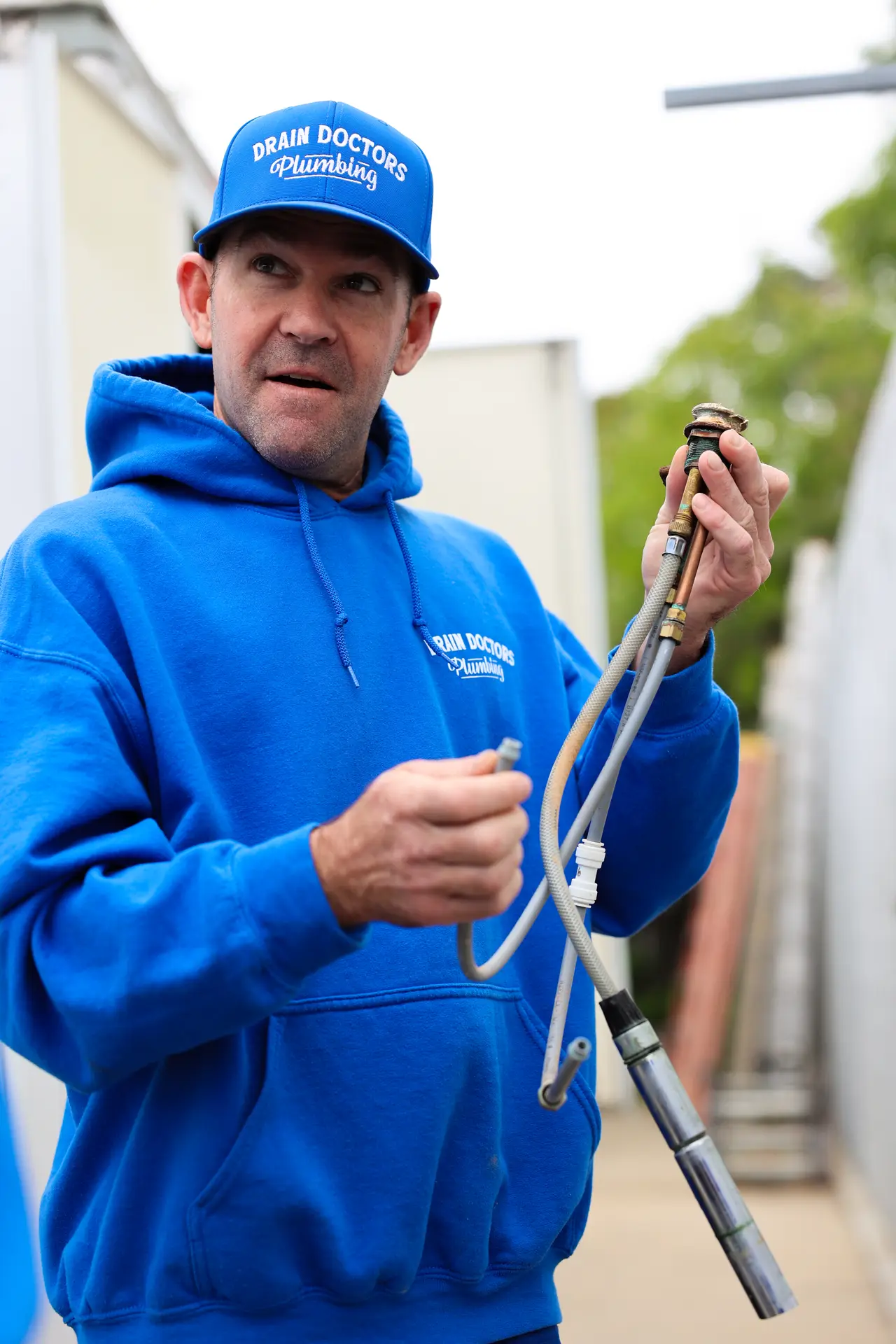 Drain Doctors Plumbing technician showing a worn faucet and supply lines removed from a home