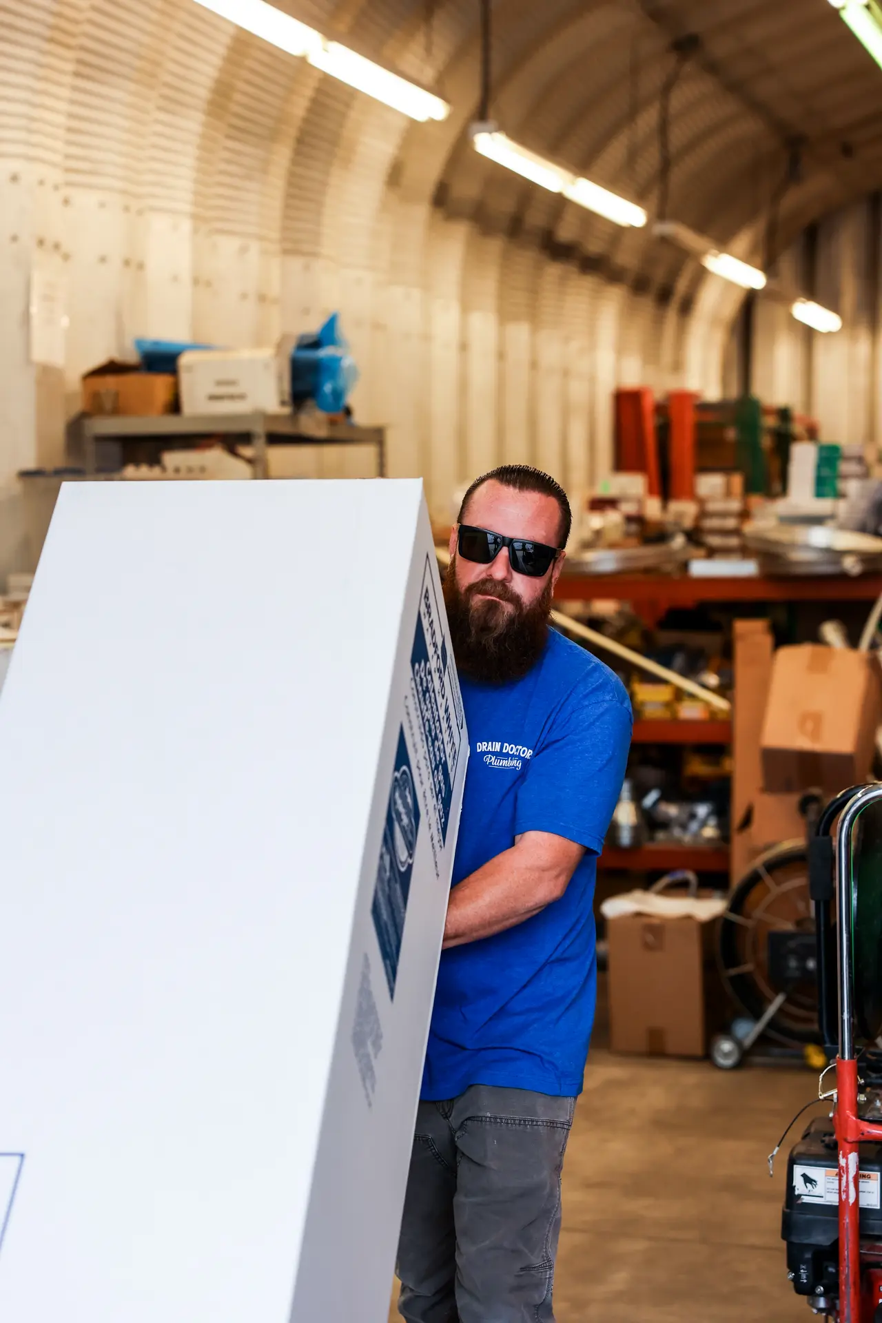 Drain Doctors Plumbing technician moving a boxed replacement water heater through the company shop