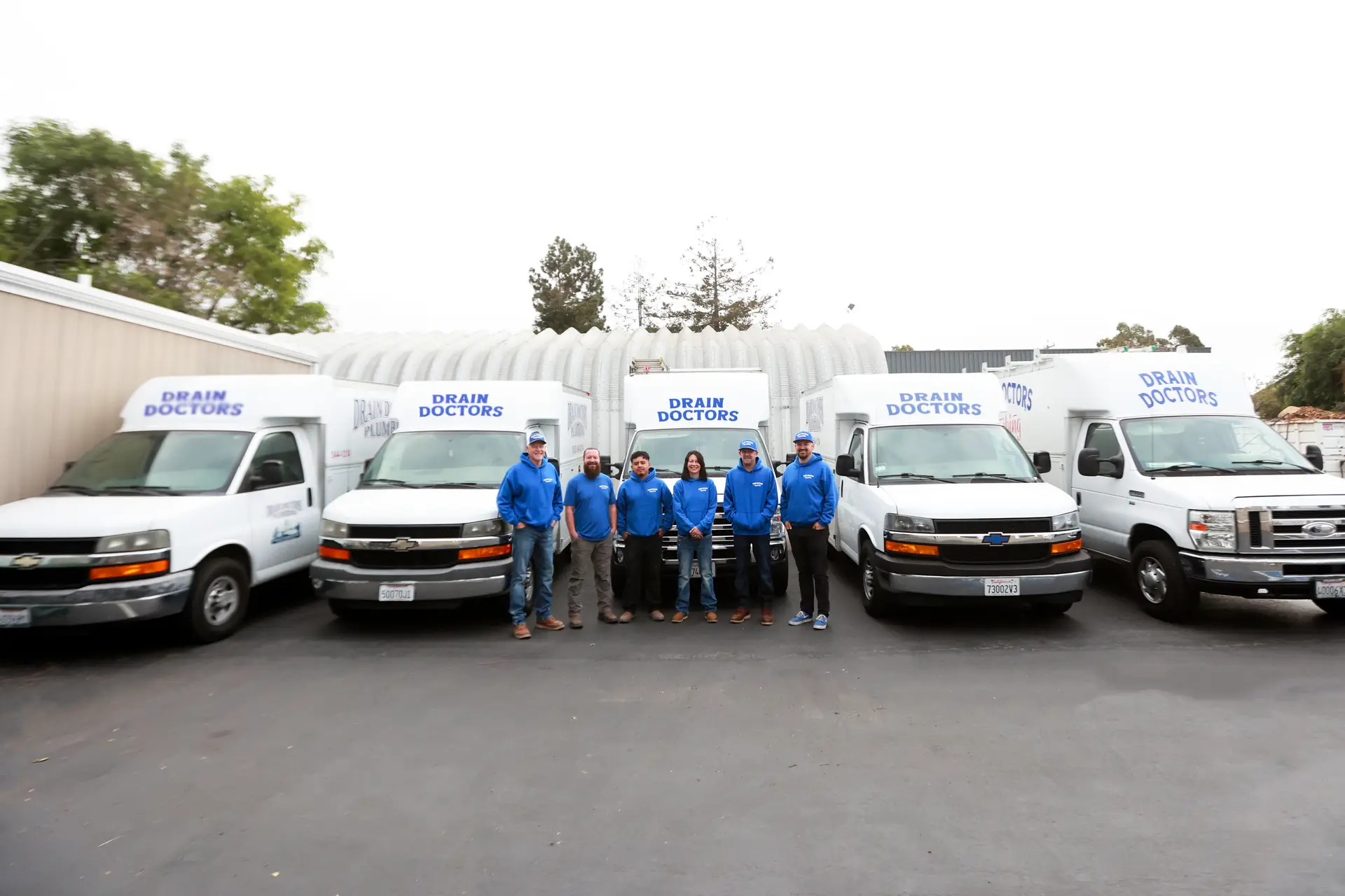 The full Drain Doctors Plumbing team lined up in front of the service fleet